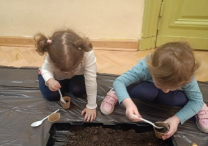 dzieci nasypują ziemię do doniczek
